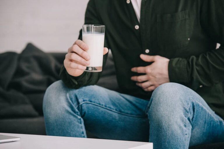 Cropped view of man with glass of milk holding stomach